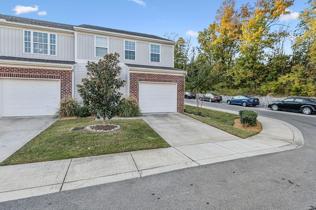 view of front of property with driveway, a front yard, a garage, and brick siding