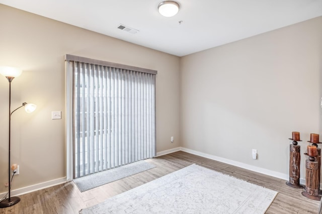 unfurnished room featuring wood finished floors, visible vents, and baseboards