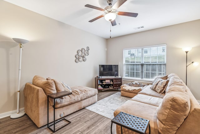 living room with a ceiling fan, visible vents, baseboards, and wood finished floors