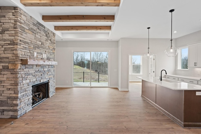 kitchen featuring light wood finished floors, a fireplace, light countertops, and a sink