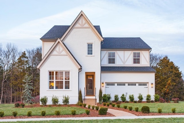 tudor-style house with a front lawn, an attached garage, and brick siding