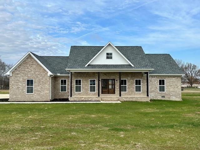 back of property featuring a yard, brick siding, roof with shingles, and a porch