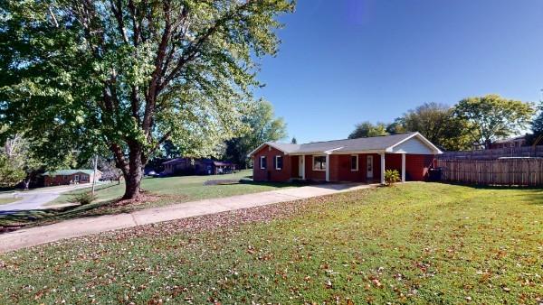 view of front of home featuring fence, a front lawn, and concrete driveway