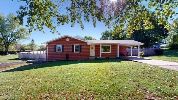 ranch-style home with a front yard, fence, a carport, and concrete driveway