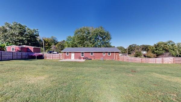 rear view of house with a fenced backyard and a yard