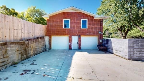 view of home's exterior featuring brick siding, driveway, an attached garage, and fence