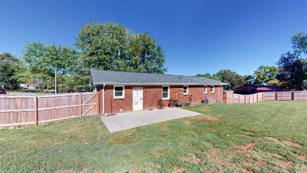 rear view of house featuring brick siding, a lawn, a patio area, and a fenced backyard