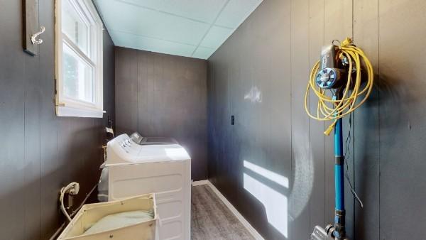 washroom featuring laundry area, washing machine and dryer, wood finished floors, and wood walls