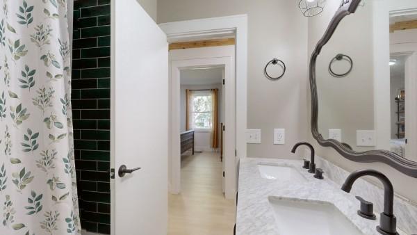 full bath featuring double vanity, a shower with curtain, a sink, and wood finished floors