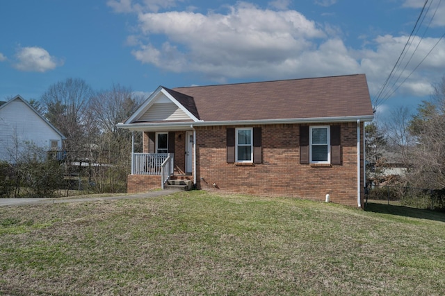 view of front facade featuring brick siding, roof with shingles, a porch, fence, and a front lawn