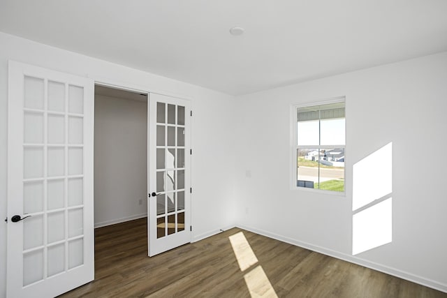 unfurnished room featuring french doors, baseboards, and wood finished floors