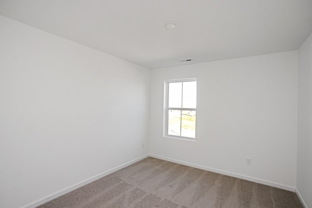 empty room featuring visible vents, baseboards, and light colored carpet