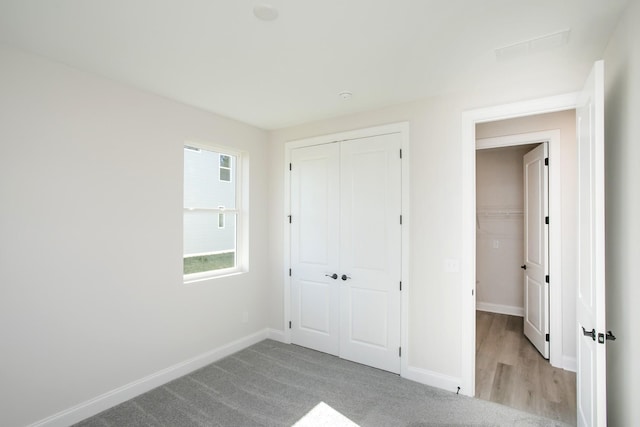 unfurnished bedroom featuring light carpet, a closet, and baseboards