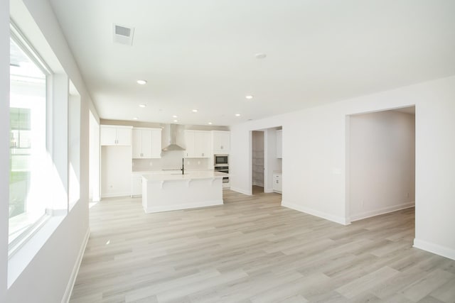 unfurnished living room with light wood finished floors, baseboards, and recessed lighting