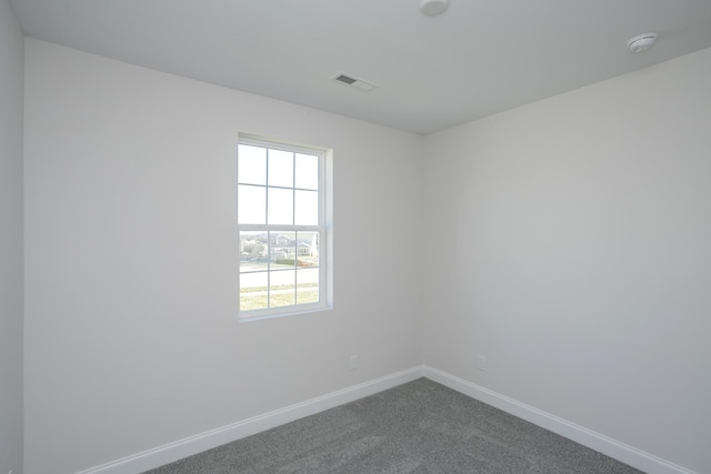 spare room with baseboards, visible vents, and dark carpet