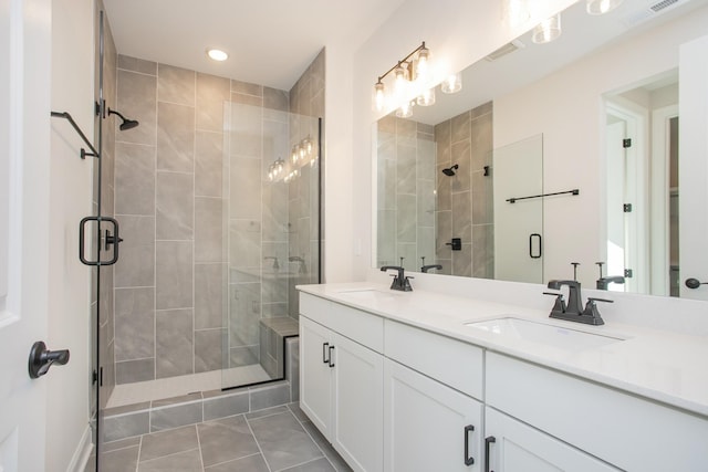 bathroom with double vanity, a shower stall, visible vents, and a sink