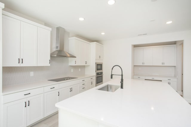 kitchen featuring tasteful backsplash, visible vents, wall chimney exhaust hood, appliances with stainless steel finishes, and a sink