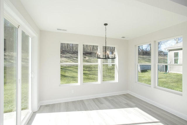 unfurnished dining area with visible vents, light wood finished floors, baseboards, and an inviting chandelier