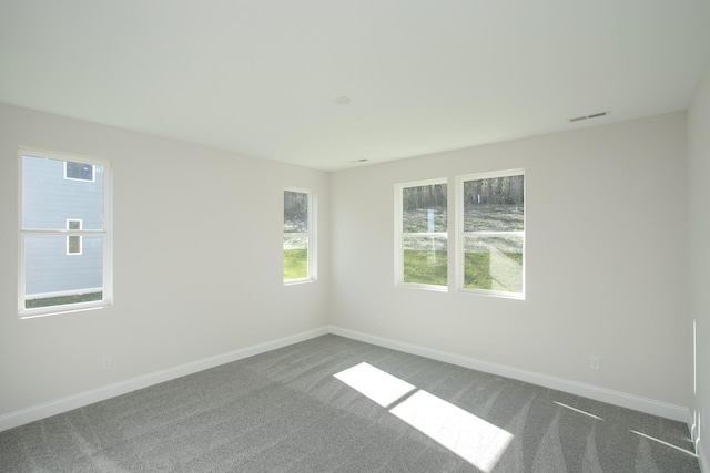 empty room featuring dark colored carpet, visible vents, and baseboards