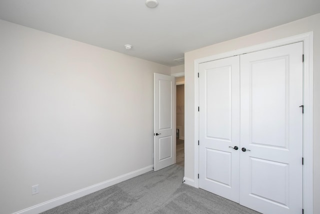 unfurnished bedroom with baseboards, a closet, and light colored carpet