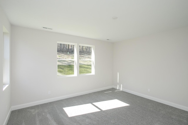 carpeted empty room featuring visible vents and baseboards