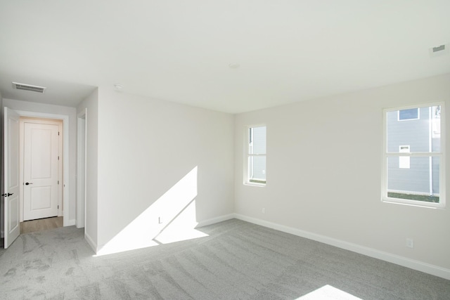 empty room with carpet flooring, visible vents, and baseboards