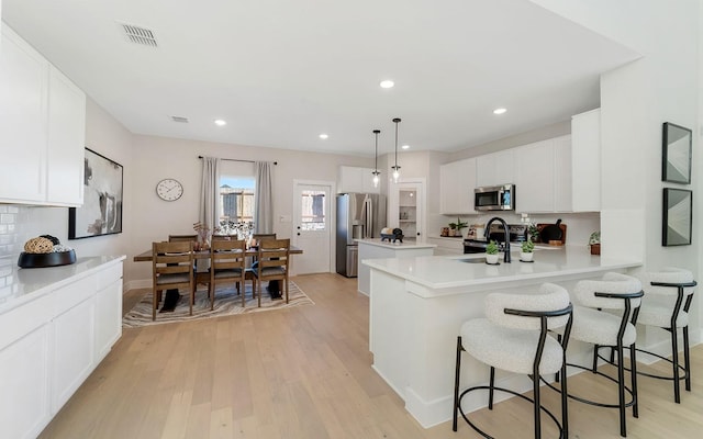 kitchen with backsplash, a peninsula, stainless steel appliances, and light wood-style floors