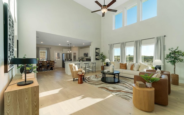 living room with baseboards, a ceiling fan, and light wood finished floors