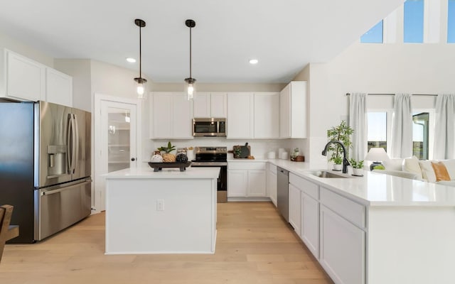 kitchen featuring a center island, light wood-type flooring, light countertops, stainless steel appliances, and a sink