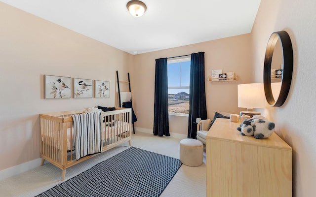 carpeted bedroom featuring baseboards and a crib