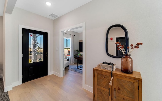 entryway with light wood finished floors, visible vents, and baseboards