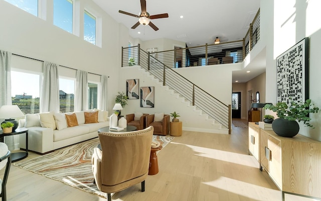 living room featuring stairs, plenty of natural light, baseboards, and light wood finished floors