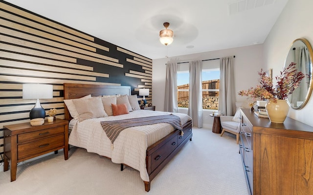 bedroom with visible vents, light colored carpet, and an accent wall