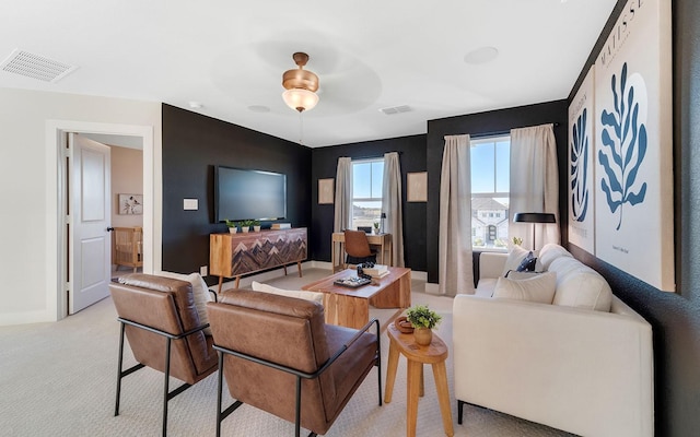 living area featuring visible vents, light carpet, baseboards, and ceiling fan