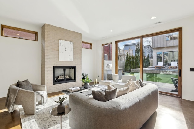 living room with recessed lighting, visible vents, a fireplace, and concrete floors