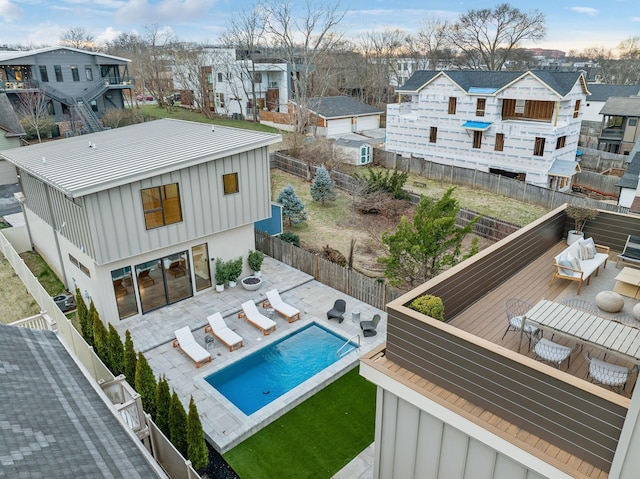 rear view of house featuring board and batten siding, a residential view, a fenced backyard, and an outdoor living space