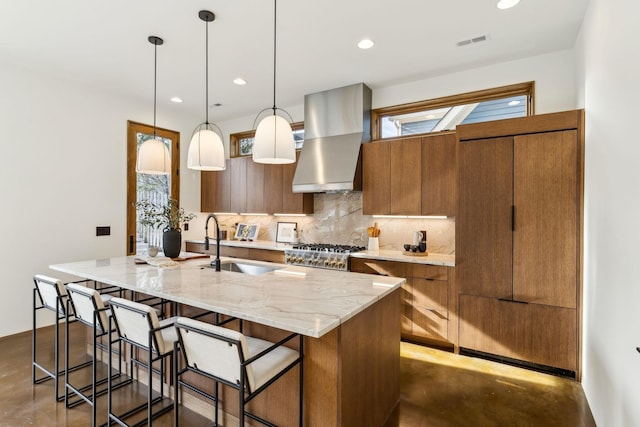 kitchen featuring wall chimney exhaust hood, concrete floors, a sink, and brown cabinetry