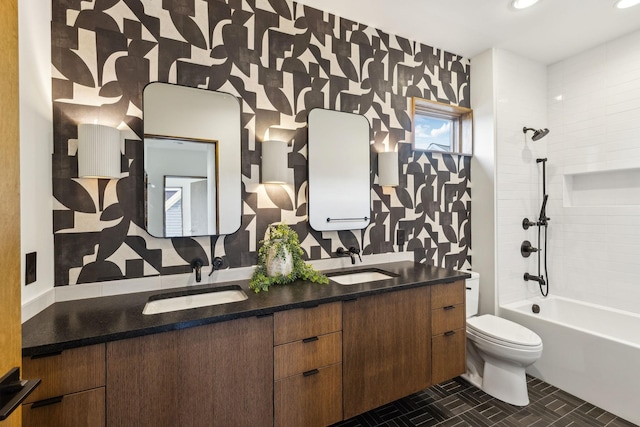 bathroom with double vanity, shower / tub combination, a sink, and toilet