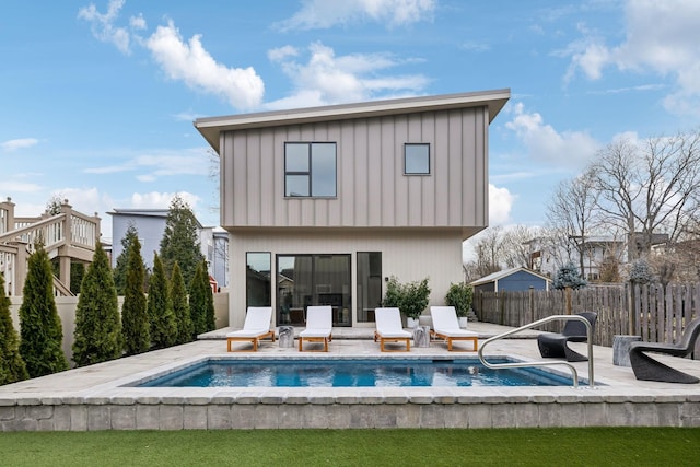 back of property with board and batten siding, a patio area, fence, and a hot tub