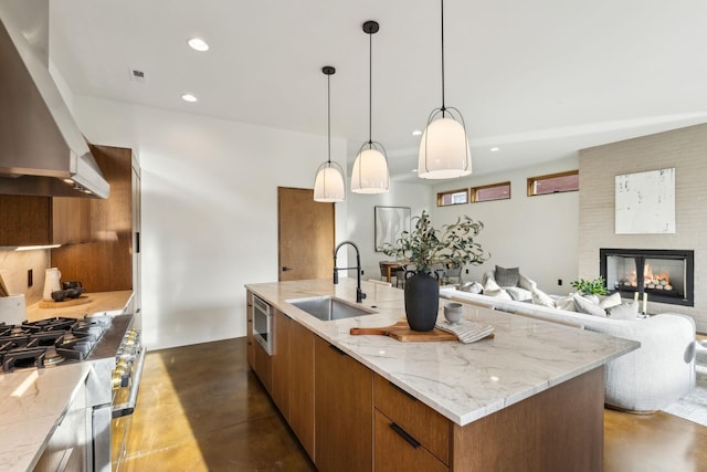 kitchen with exhaust hood, a sink, open floor plan, brown cabinets, and finished concrete floors