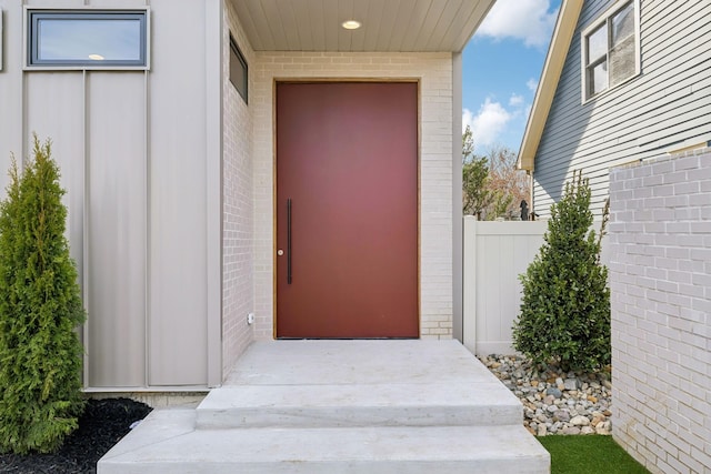 property entrance with brick siding and fence