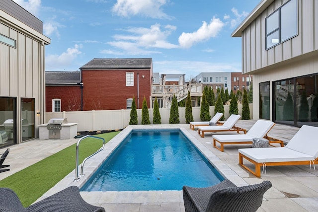 view of pool featuring a fenced in pool, grilling area, a patio area, fence, and exterior kitchen