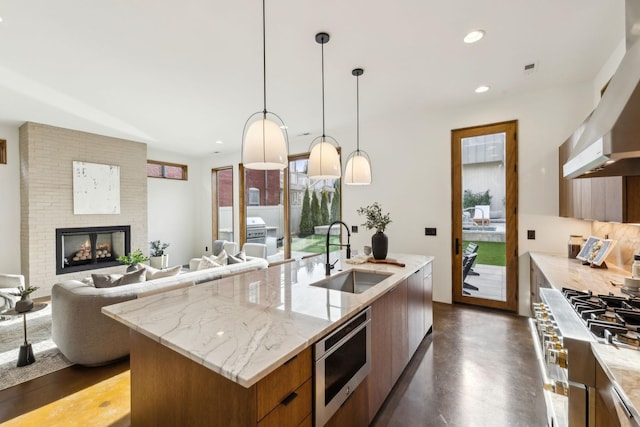 kitchen featuring a fireplace, stainless steel microwave, a sink, modern cabinets, and exhaust hood