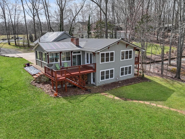 rear view of house featuring a chimney, a yard, metal roof, a wooden deck, and a sunroom