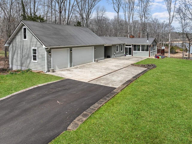 ranch-style house featuring aphalt driveway, a garage, a front lawn, a sunroom, and metal roof
