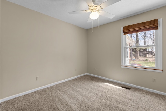 carpeted empty room featuring baseboards, a ceiling fan, and visible vents