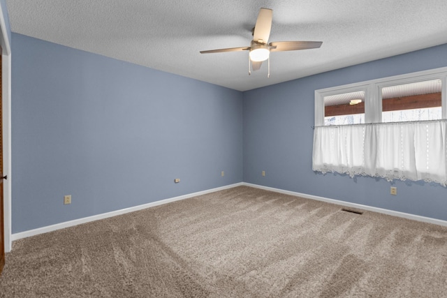carpeted empty room with ceiling fan, baseboards, and a textured ceiling