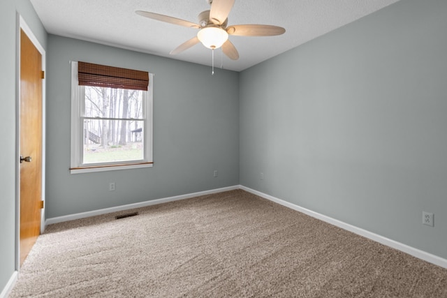 empty room featuring visible vents, carpet flooring, baseboards, and ceiling fan