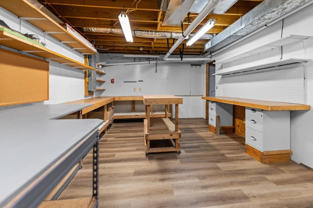 unfinished basement with wood finished floors and a workshop area