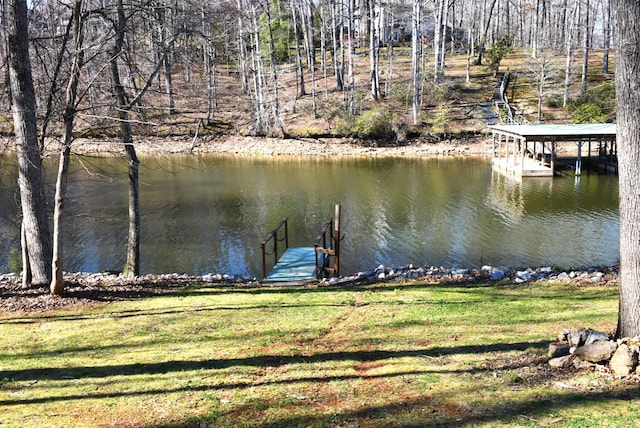 view of dock with a lawn and a water view